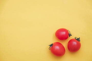 Red tomatos vegetable on a yellow background. Top view. Minimalist Style. Copy, empty space for text