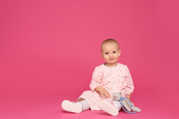 Cute little child playing with knitted toy on pink background. Space for text