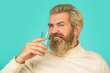 Bearded man drinking water. Male drinking from a glass of water. Health care concept photo, lifestyle, close up. Happy beard man drinking water. Smiling male holding transparent glass in her hand