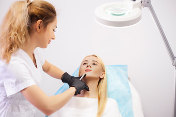 Woman receives injection for lip augmentation at cosmetology clinic