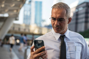 Senior CEO businessman with smartphone in city