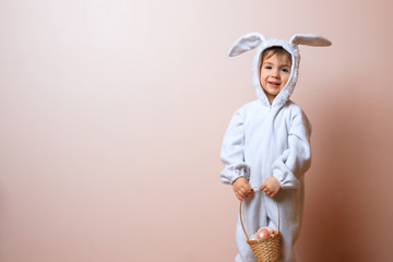 Cute little child boy wearing bunny costume on Easter day. Boy with Easter eggs in the basket.