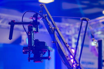 Professional video shooting. Concept - organization of video recording of an event. Crane for camcorder. Metal faucet with a fixed camera. Professional camera on the background of the concert venue