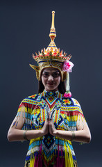 The beautiful woman wearing Thai southern folk dancing costume,made from colorful bead,put headdress on her head,prepare for racticing  and showing preformances,on solid backdrop