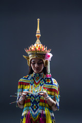 The beautiful woman wearing Thai southern folk dancing costume,made from colorful bead,put headdress on her head,prepare for racticing  and showing preformances,on solid backdrop