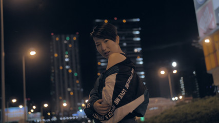 Fototapeta na wymiar Korean girl posing at night on the street against the background of skyscrapers