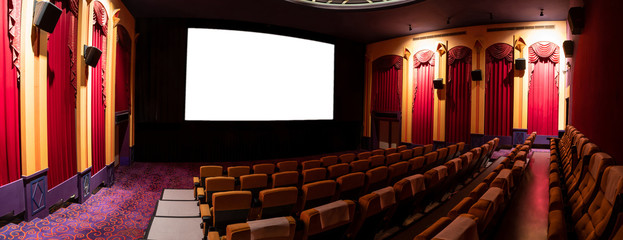 Cinema theater screen in front of seat rows in movie theater showing white screen projected from...