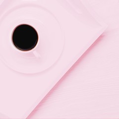 Pale pink cup of black coffee on a pink wooden background. Copy space