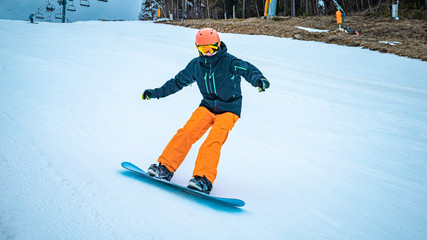 Male teenager taking a turn with his snowboard on a cloudy day