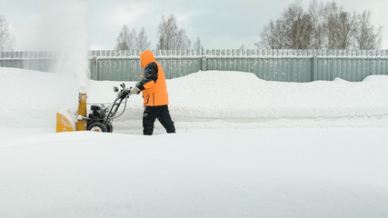 Man cleans snow with a snow thrower goes right to left