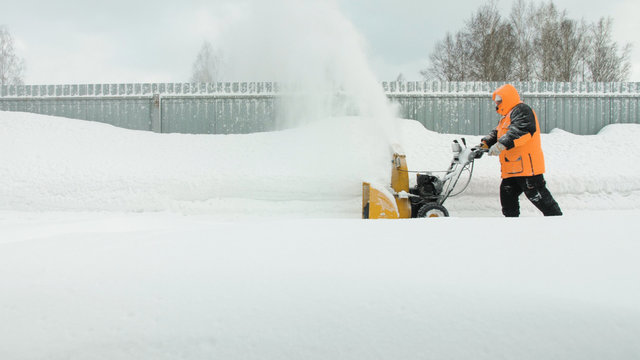 Man cleans snow with a snow thrower goes right to left
