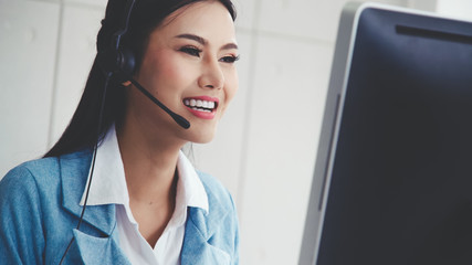 Customer support agent or call center with headset works on desktop computer while supporting the customer on phone call. Operator service business representative concept.