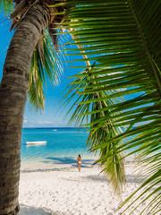 Naklejka premium Young woman in bikini relaxing at tropical palm beach. Tropical vacation