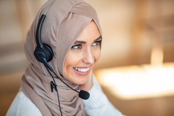 Portrait of a friendly young muslim call center agent working in a modern office. Portrait of...