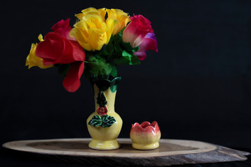 Artificial flowers in pot in dark studio background