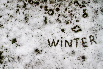 The word Winter is written on white snow. First snow. The grass is visible under the snow. A thin layer of snow. Background. Copy space.