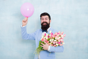 Art of charm. Happy hipster go out on date. Bearded man hold tulips and balloon. Perfect first date flowers. Floral gift for romatic date. Valentines day. Beautiful flowers to impress with on date