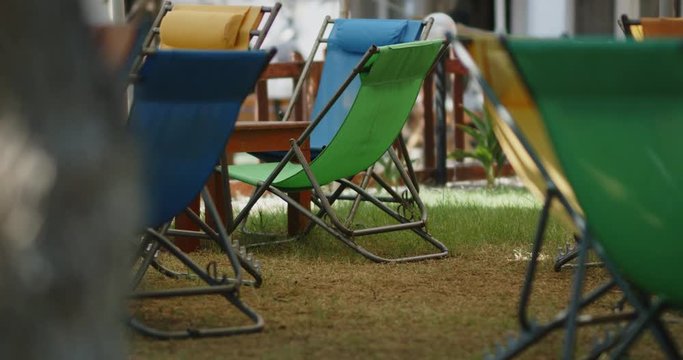 Empty camp chairs sit on the lawn of a park during a outdoor concert.