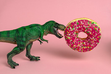 funny card with dinosaur with open mouth bites strawberry donut on a pink background
