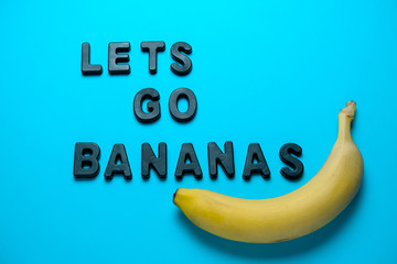 inscription lets go bananas and fresh yellow banana on a blue background