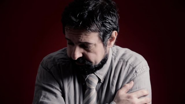 A depressed, powerless man's expression. Shot with artistic intentional darkness and contrast. Part of a series of depictions of feelings and emotions with professional actors.