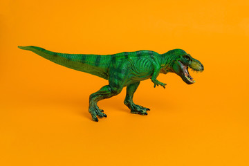 green dinosaur toy with open mouth on a vivid orange background