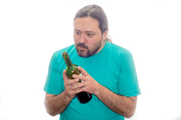 An unshaven young man holds a bottle of wine with both hands and does not stare intently.