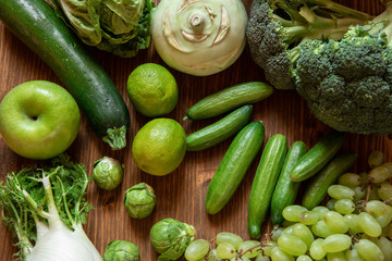 grünes Gemüse und Obst auf brauner Platte aus Holz