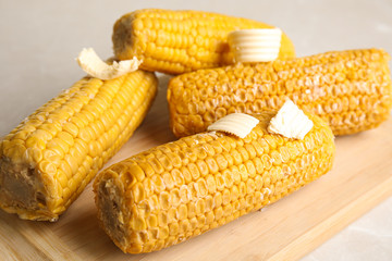 Delicious boiled corn with butter on wooden board, closeup