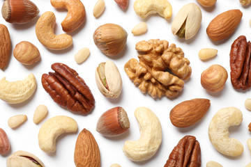 Different delicious nuts on white background, flat lay
