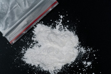 Cocaine or other illegal drugs, white powder, syringe, isolated on black glossy background