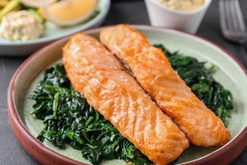 Tasty salmon with spinach on table, closeup