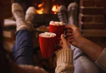 Zelfklevend Fotobehang Lovely couple with sweet cocoa near fireplace indoors, closeup © New Africa