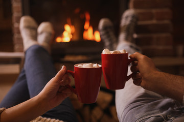 Lovely couple with sweet cocoa near fireplace indoors, closeup