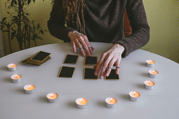 young woman lays out black cards on the table with candle lights