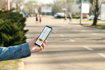 Woman ordering taxi with smartphone on city street, closeup