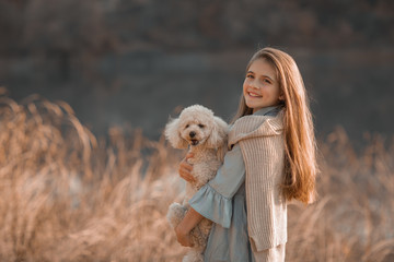 A girl walks with a dog in a meadow.