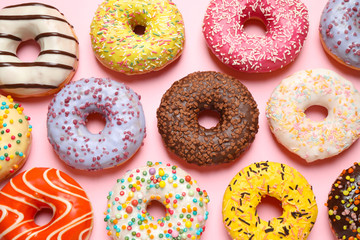 Delicious glazed donuts on pink background, flat lay