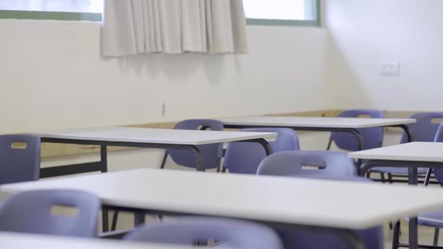 Empty classroom in school - pan across empty desks and chairs