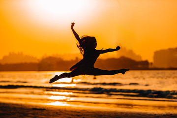 Fototapeta na wymiar Adorable happy little girl on white beach at sunset.