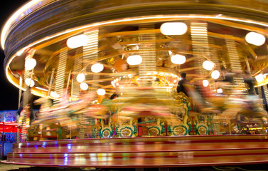 Obraz premium long exposure view of fairground ride at night with light trails and motion blur