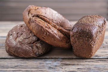 three loaves of rye -wheat bread of round, oval and rectangular shape on a wooden table . home-baked bread