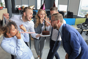 Obraz premium Happy business team with birthday cake are greeting colleague at office party