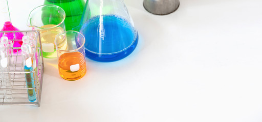 Photo of Chemistry glassware with colored liquid putting together on white modern desk in orderly laboratory. Orderly scientific working table concept.