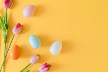 close up top view group of Easter eggs and tulip flowers on yellow pastel color background with copy space for design in festival concept