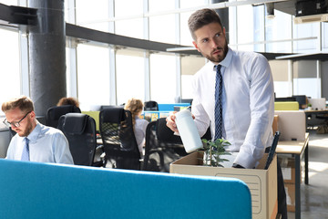 Sad dismissed worker are taking his office supplies with him from office