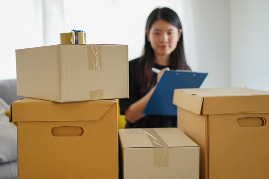 Asian woman checking and packing the carton box prepare to move to new house or check package before send to customer from shopping online by checklist with blur motion, packing and checklist concept