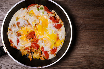 Fried eggs in a frying pan for breakfast on a wood background