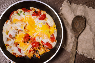 Fried eggs in a frying pan for breakfast on a wood background