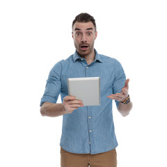 Amazed casual man holding tablet and gasping